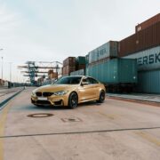 gold BMW next to a shipping container